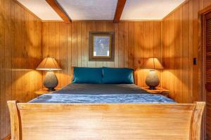 1 cama en una habitación con paredes de madera y 2 lámparas en Big Bear Cave, en Blue Ridge