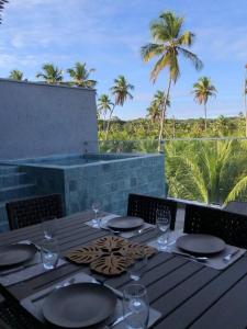 a wooden table with plates and wine glasses on it at Recanto dos Coqueirais in São Miguel dos Milagres