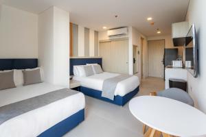 une chambre d'hôtel avec deux lits et une table dans l'établissement Increible Apartasuit a solo 3 min de la playa, à Santa Marta 14 autres photos