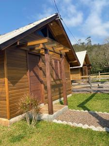 プライア・グランデにあるCabana Refúgio canyon Malacaraのポーチと芝生のある小さな木造の建物