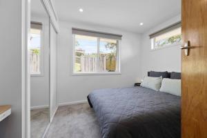 a bedroom with a bed and two windows at 3 bedroom, pet friendly home CBD in Warrnambool