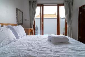 a bedroom with a white bed with a large window at kenanga Villa Ubud in Ubud +12 photos
