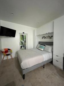 a white bedroom with a bed and a chair at Luna y Sol Calle 8 in Miami