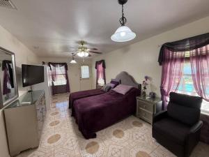 a bedroom with a bed and a tv and a chair at Casa Colibrí in Harlingen
