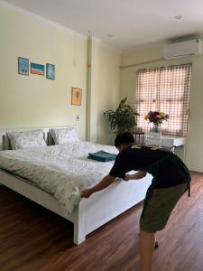 un hombre está haciendo una cama en un dormitorio en HCA Homestay, en Ha Giang 14 fotos más