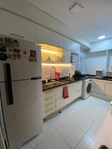 a kitchen with a white refrigerator and a sink at Pontal Beach Loft I in Rio de Janeiro