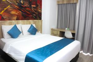 a bedroom with a bed with a painting on the wall at Urban Hotel Serpong in Banten