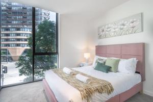 una camera da letto con un letto grande con una grande finestra di Immaculate 1br Apt In Docklands Pool Free Parking a Melbourne