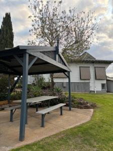 a picnic shelter with two benches in front of a house at Bacchus Marsh Caravan Park in Bacchus Marsh