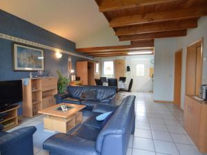 a living room with blue leather couches and a table at Apartment with balcony in the Gransdorf Eifel in Gransdorf