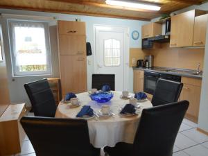 eine Küche mit einem Tisch mit Stühlen und einem Tisch mit Stühlen und einer Tableasteryasteryasteryasteryastery in der Unterkunft Apartment with balcony in the Gransdorf Eifel in Gransdorf