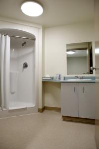 a bathroom with a shower and a sink and a mirror at Residence & Conference Centre - Hamilton in Hamilton