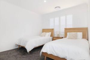 ダンズボローにあるNewly Built Luxury Modern Homeの白いベッドルーム(ベッド2台、窓付)