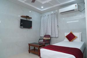 a bedroom with a bed and a tv and a chair at HOTEL THANVI iNN in Guntūr +18 photos