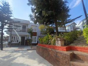a white house with a tree in front of it at Tersha Homestay 2BHK in Shillong