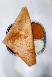 a pita sandwich and a dipping sauce in a container at Hotel Harihar Atithi Bhawan in Naimishāranya