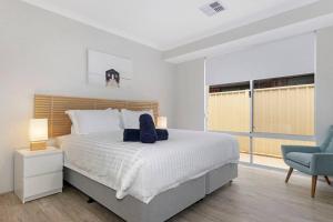 ein Schlafzimmer mit einem großen Bett und einem blauen Stuhl in der Unterkunft Brand New Home Dunsborough in Dunsborough