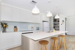 eine Küche mit weißen Schränken und Barhockern in der Unterkunft Brand New Home Dunsborough in Dunsborough