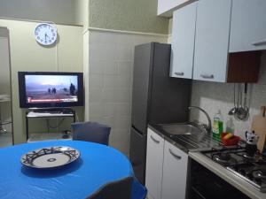a small kitchen with a blue table and a tv at Ultra central Salerno vicino alla Stazione e il mare in Salerno