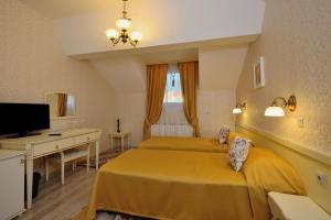 a bedroom with two beds and a desk and a television at Villa Paris in Hisarya