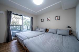 Dos camas en un dormitorio con una gran ventana. en Zabo Hills 202, en Sapporo