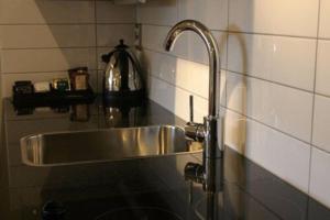 a kitchen sink with a faucet on a tiled wall at Athena Motel in Christchurch +70 photos