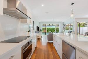 a kitchen with white countertops and a dining room at Casuarina Calm - Beach House with Pool by uHoliday in Casuarina