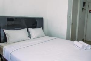 a large white bed with two white towels on it at Comfort Stay Studio Room at Poris 88 Apartment By Travelio in Tangerang
