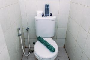 a bathroom with a toilet with a green hose on it at Comfort Stay Studio Room at Poris 88 Apartment By Travelio in Tangerang +10 photos
