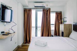 a bedroom with a white bed and a television at Comfort Stay Studio Room at Poris 88 Apartment By Travelio in Tangerang