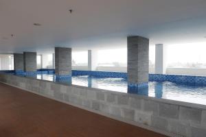 a large swimming pool with blue tiles in a building at Comfort Stay Studio Room at Poris 88 Apartment By Travelio in Tangerang