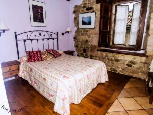 1 dormitorio con cama y pared de piedra en Posada Corral Mayor en La Serna