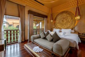 a bedroom with a bed and a couch and a balcony at Sawasdee Village in Kata Beach