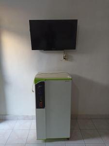 Tokomang Homestay في ليغِيان: ثلاجة صغيرة مع تلفزيون بشاشة مسطحة على الحائط