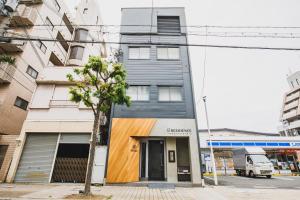 a building on a street with a tree in front at R Residence 天下茶屋 IV in Osaka