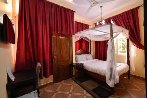 a bedroom with a canopy bed and red curtains at East Point Hotel Moshi in Moshi