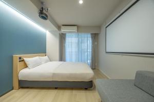 1 dormitorio con cama y pantalla de proyección en Minn Umeda Nakazakicho, en Osaka