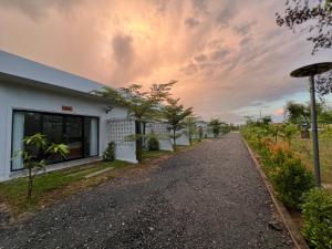 a road in front of a white building with trees at Diamonich Suites Hotel in Angk Ta Saom