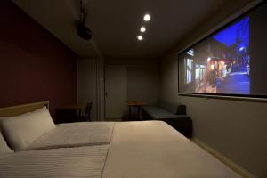 Un dormitorio con una cama y un televisor de pantalla plana. en Minn Umeda Nakazakicho, en Osaka 19 fotos más