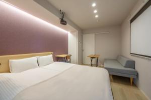 1 dormitorio con cama, silla y pantalla de proyección en Minn Umeda Nakazakicho, en Osaka