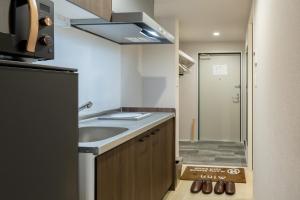 Una pequeña cocina con fregadero y refrigerador. en Minn Umeda Nakazakicho, en Osaka