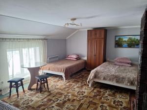 Un dormitorio con dos camas y una mesa y sillas. en Садиба "Барвінок", en Podobovets