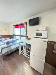 a hotel room with two beds and a table and a microwave at SHINJUKU WARM VILLA I in Tokyo