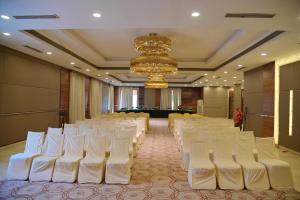 a banquet hall with white chairs and a chandelier at Rang Lords Inn Bharuch in Bharuch