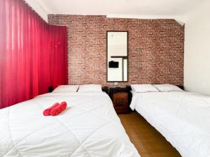 two beds in a room with red pillows on them at Alam Citra BnB Mitra RedDoorz in Yogyakarta