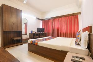 a bedroom with a bed and a desk and a television at FabHotel Darshan Tower in Nagpur