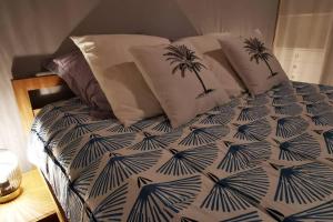 Una cama con sábanas azules y blancas con dos palmeras. en Villa meublé Tourisme 4 etoiles Sous le Ficus piscine chauffée - Ouest Lagon, en Saint-Paul 85 fotos más