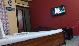 a bedroom with a bed with a tv on the wall at Goodluck Homestay in Guwahati