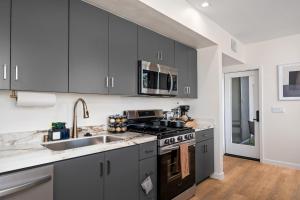 a kitchen with gray cabinets and a sink at Modern 2 Bedroom King Bed EVCharger Pet-Friendly Balcony in San Diego
