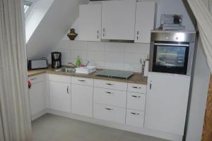 a kitchen with white cabinets and a sink at Kiebitzei in Wittdün